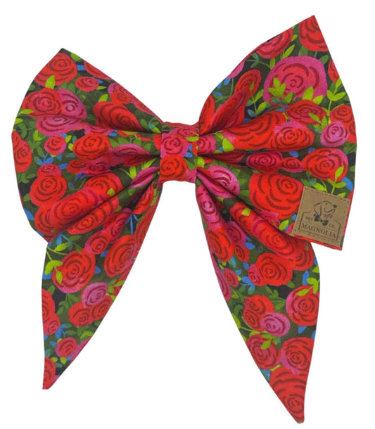 a vibrant bouquet of bright red and pink roses adorned with delicate touches of greenery