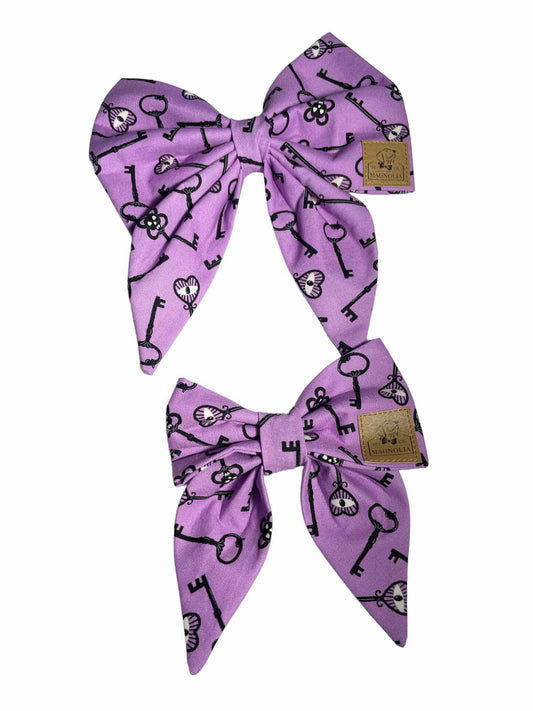 Made from vibrant purple fabric featuring a unique skeleton eye key pattern that glows in the dark, this bow is perfect for adding a touch of spooky fun to your furry friend's wardrobe
