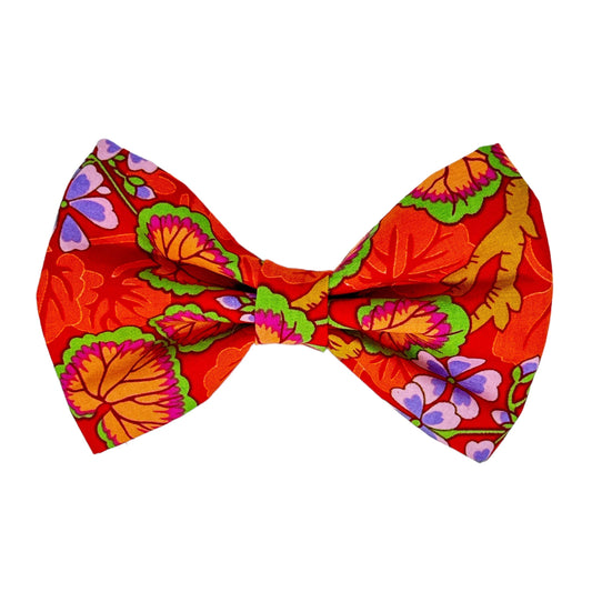 This lovely dog bow tie features a beautifully illustrated garden in shades of red, green, pink, and purple on a orange background by Magnolia Pet Company.