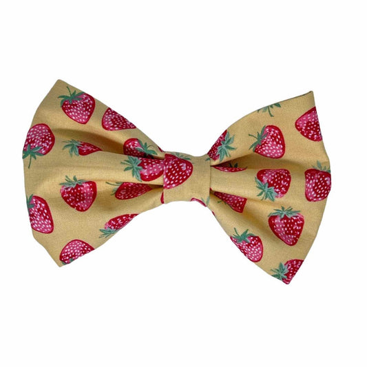 Crafted from warm yellow fabric, this charming bow features an array of pink strawberries in multiple shades, creating a delightful and vibrant accessory perfect for any dog