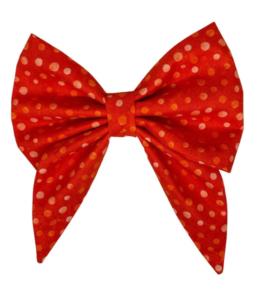 The bow is adorned with playful polka dots in shades of white, light orange, and burnt orange, creating a fun and eye-catching pattern that is sure to turn heads at the park or on your daily walks