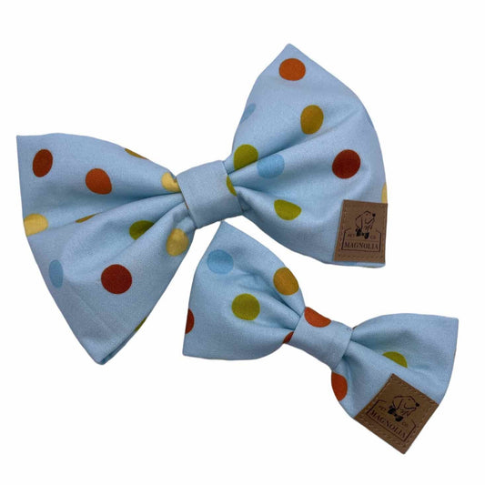 This dog bow tie features warm tones of orange, yellow, green and brown on sky blue background.