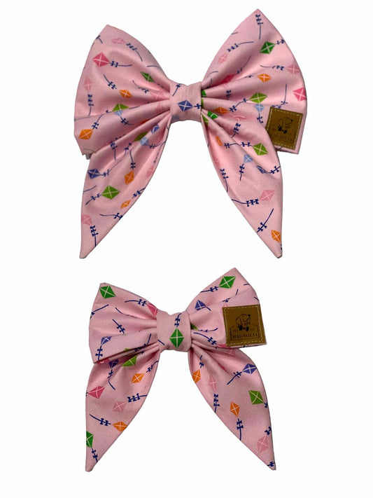 Flying Kites Dog Bow features a soft pink fabric with charming pastel kites, capturing the playful spirit of a sunny day at the park.