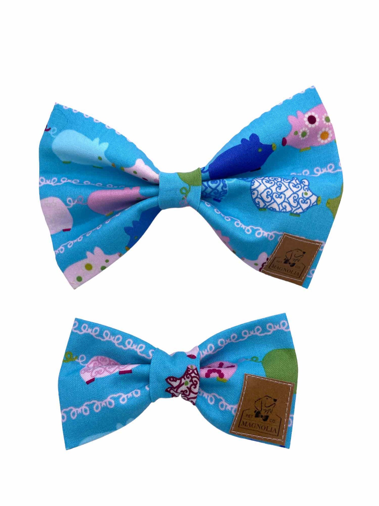 This adorable accessory features a vibrant blue fabric adorned with whimsically decorated pigs in a variety of cheerful colors