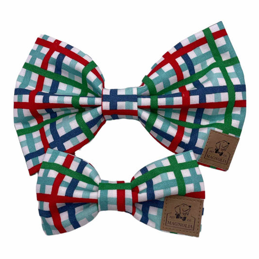 This timeless accessory features a charming plaid pattern in vibrant hues of red, aqua, green, and blue, set against a crisp white background