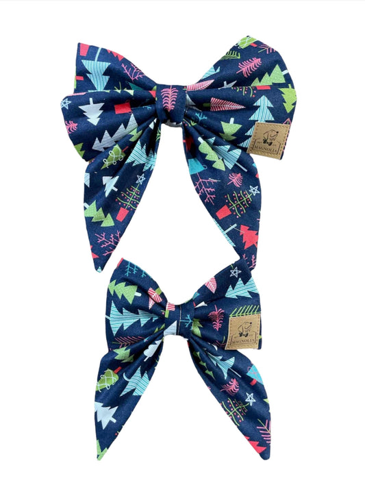 Crafted from premium navy blue fabric, this bow features a delightful pattern of whimsical trees in vibrant shades of pink, blue, and green