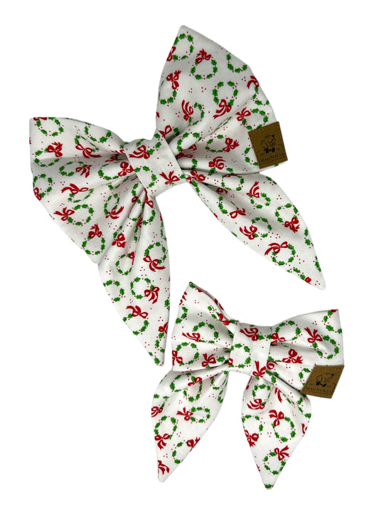 Dog bow featuring vibrant green Christmas wreaths and cheerful red bows on a white background