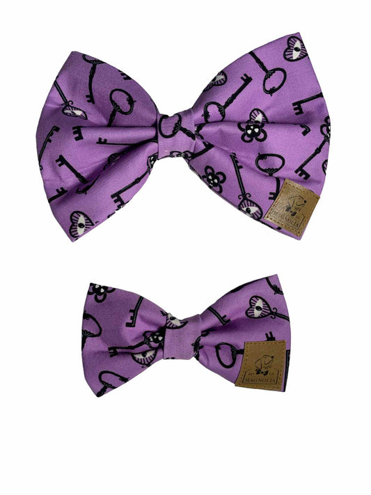 Made from vibrant purple fabric featuring a unique skeleton eye key pattern that glows in the dark, this bow is perfect for adding a touch of spooky fun to your furry friend's wardrobe.