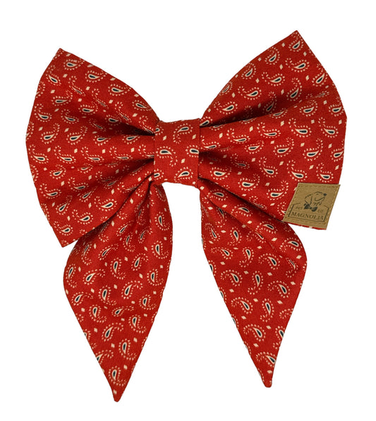 This exquisite dog bow features a rich crimson backdrop adorned with a delicate paisley design in shades of red, beige, and blue.