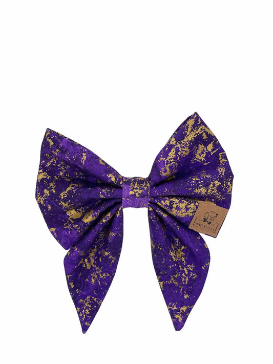 This luxurious accessory is crafted from deep, rich purple fabric, accented with enchanting splashes of gold glitter
