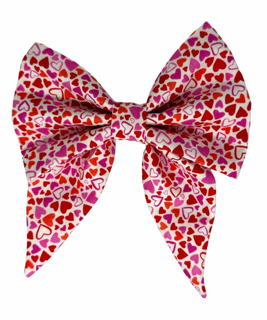 This delightful dog bow tie features an array of hearts in shades of purple, pink, and red, perfect for any stylish dog.