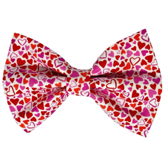 This delightful dog bow tie features an array of hearts in shades of purple, pink, and red, perfect for any stylish dog.
