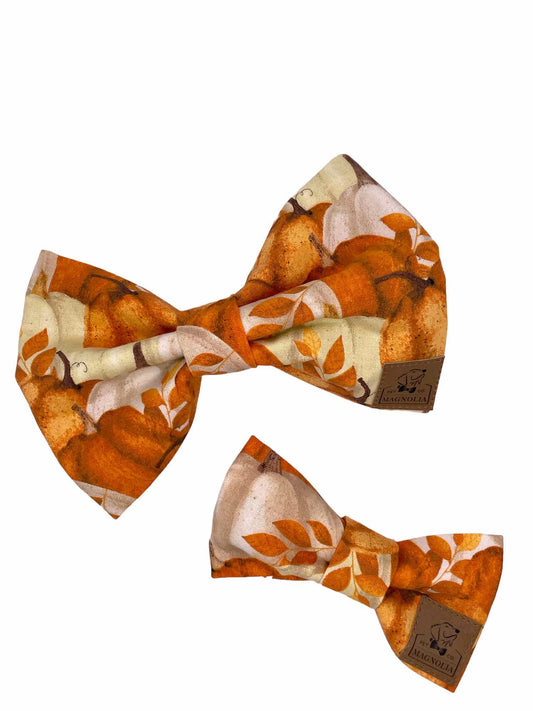 This delightful accessory features a soft cream background, providing a warm and neutral canvas that highlights the vibrant array of pumpkins scattered across the fabric.
