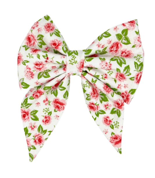 Transform your furry friend into a style icon with our Vintage Rose on White Bow. This beautifully crafted accessory features a pristine white fabric adorned with delicate pink roses, subtly accented with hints of green leaves. 