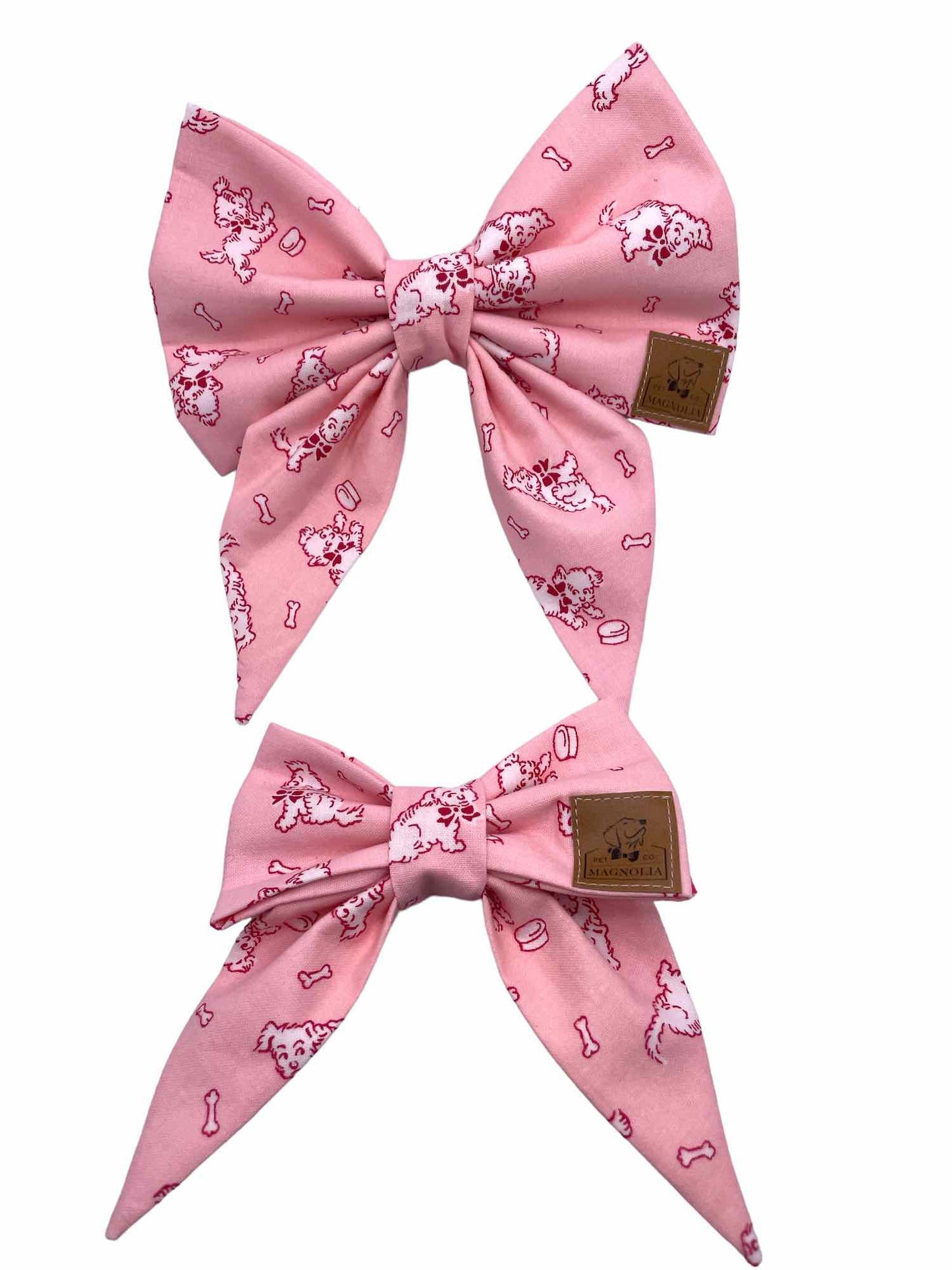 This charming accessory features a soft pink background, providing a delicate and stylish look. Each bow is adorned with a playful white dog design, beautifully outlined in hot pink, giving it a delightful pop of color. The pattern is completed with cute little dog bowls and bones