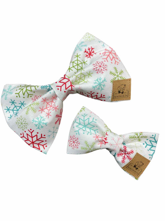 This enchanting accessory features pristine white fabric adorned with delicate snowflakes in light pink, blue, and green