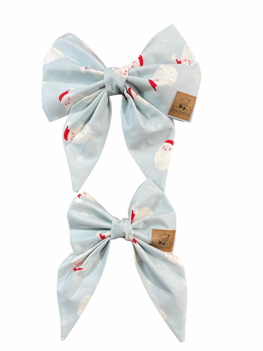 Celebrate the holiday season in style with our adorable dog bow featuring a jolly Santa &nbsp;face on a light blue fabric background.